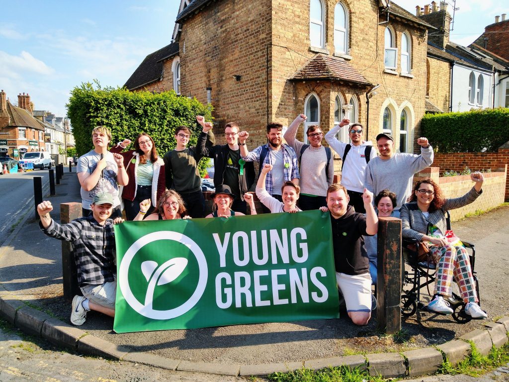 Group of Young Greens in Oxford with the Young Greens banner. They're all smiling with their fists raised