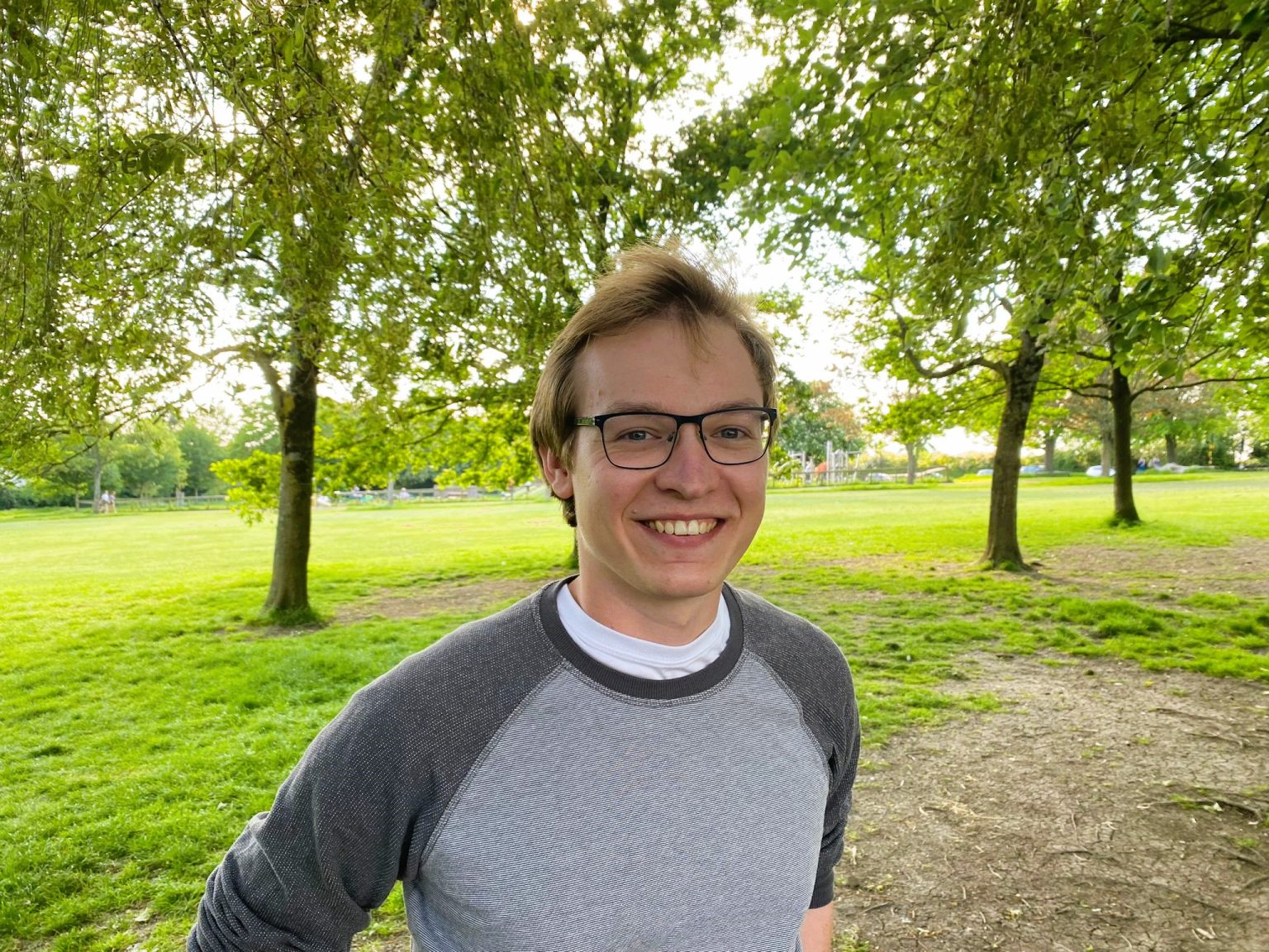 James smiling to camera with a lush green background